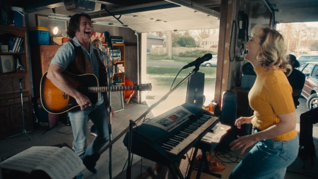 Hugh Jackman and Kate Hudson as Mike and Claire Sardina rehearse together in a garage scene from the upcoming musical drama Song Sung Blue. Image courtesy of Focus Features.