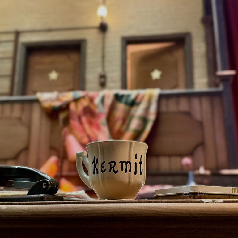 A production still provided by Disney of the iconic Muppet Show backstage area with Kermit's cup.