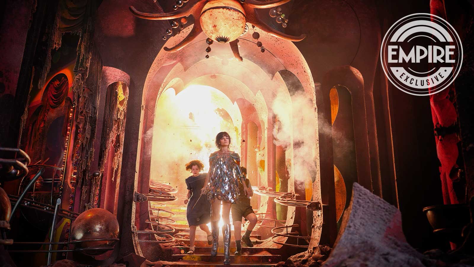Empire exclusive still from Narnia: The Magician's Nephew showing a woman in a mirrored dress leading two children through a damaged archway
