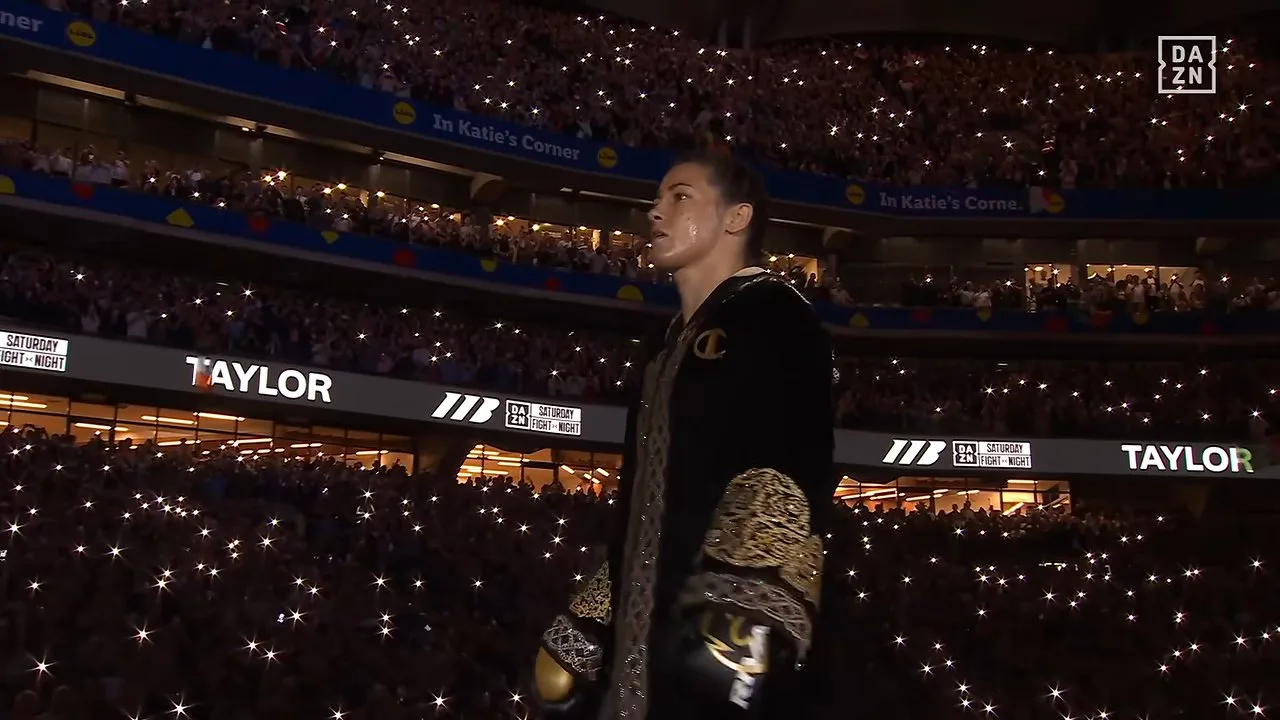 Katie Taylor walks toward the ring at Croke Park in Dublin as a sold-out crowd holds phone lights aloft during the final ring walk of her boxing career