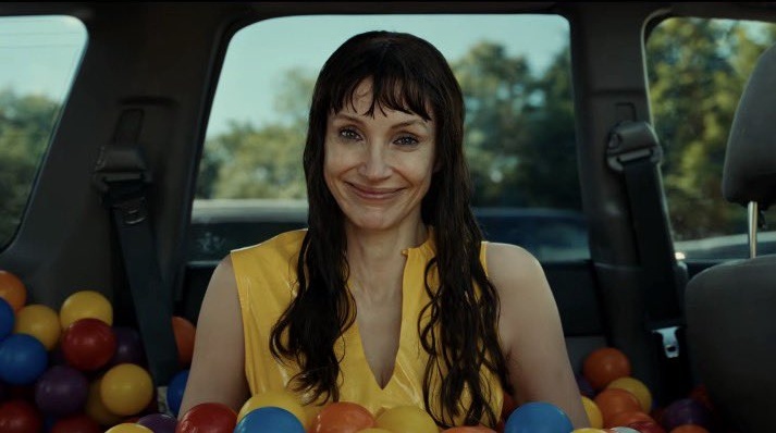 Jessica Chastain as Ursula, smiling in the back seat of a car surrounded by colorful plastic balls in a scene from Other Mommy.