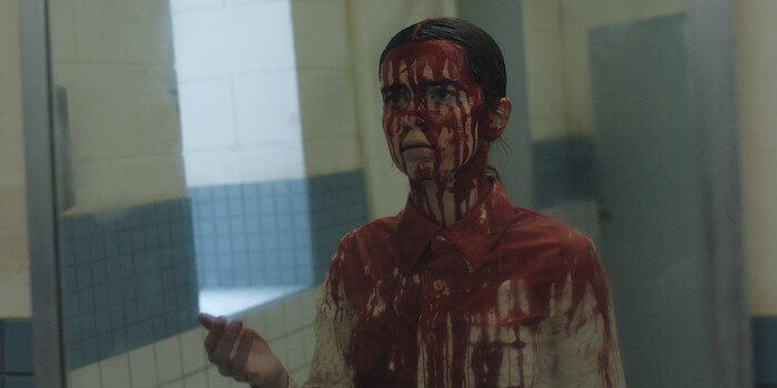 Blood-soaked Summer H. Howell as Carrie White looking into a school bathroom mirror in Prime Video's Carrie series