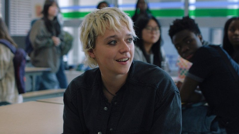 Thalia Dudek as Emaline West, smiling in the Ewen High cafeteria in Prime Video's Carrie