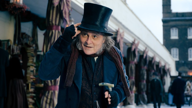 Johnny Depp as Ebenezer Scrooge tipping his top hat on a snowy Victorian street