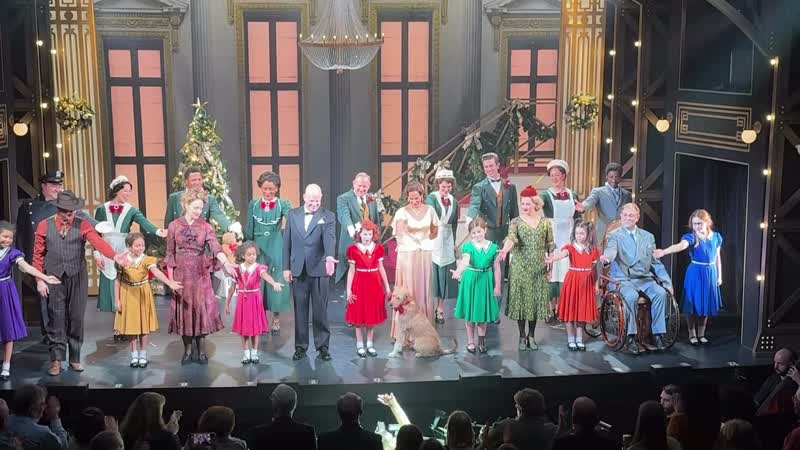 The cast of Goodspeed's Annie holding hands during the opening-night curtain call, with Laiken Jules at center and Scotty the dog seated in front of her