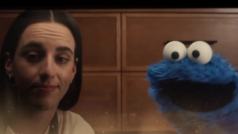 Caitlin Clark and Cookie Monster looking through an oven door at baking chocolate chip cookies