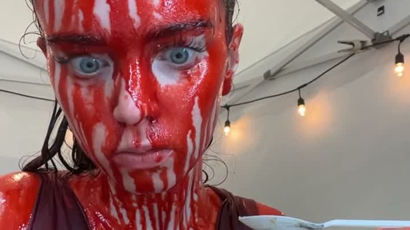 Summer H. Howell as Carrie White, covered in fake blood while eating dessert on the Carrie set