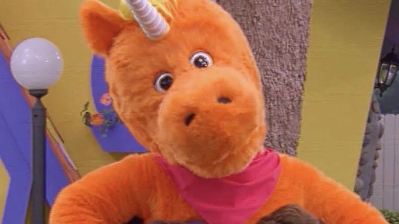 Buddy, the bright orange unicorn host of the fictional children's show It's Buddy!, in a scene from the film Buddy