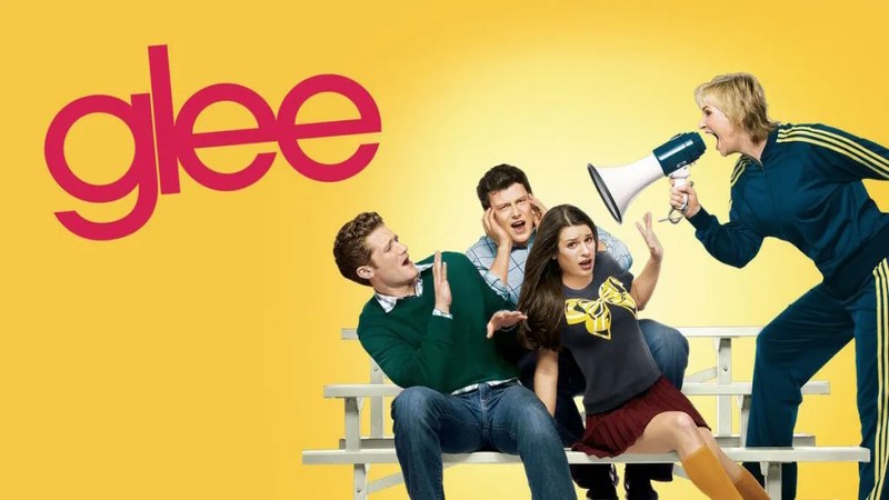 Original Glee key art: cast members sit on the McKinley High bleachers while Sue Sylvester shouts through a megaphone, next to the show's red logo on a yellow background